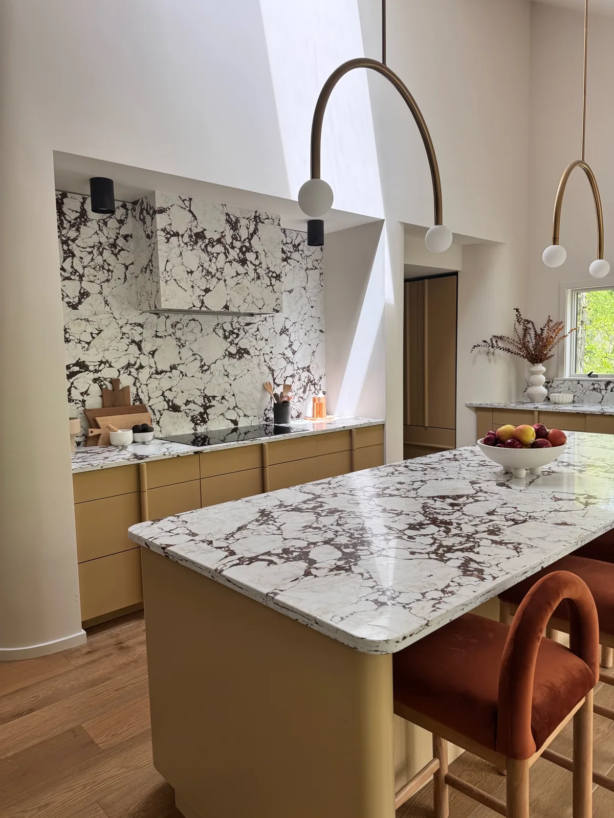 Kitchen with Calacatta marble island, brass arch faucet, and custom millwork